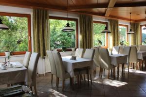 恩格尔哈茨采尔候格斯坦埃德尔家庭膳食公寓酒店的餐厅设有白色的桌椅和窗户。