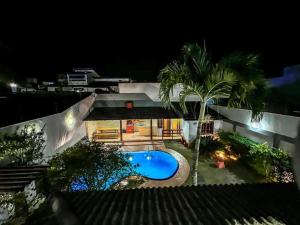 瓜拉派瑞Casa Paris 481 - Sua Mansão na Praia do Morro的享有房子的景色,在晚上设有游泳池