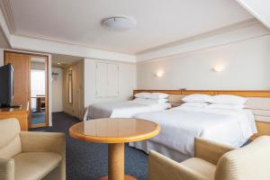 浦安东京湾喜来登大酒店 的酒店客房带两张床和一张桌子以及椅子。