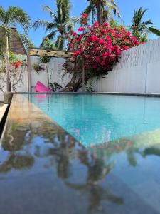 吉利特拉旺安Villa Luna Sunset Beach的一座拥有粉红色花卉和围栏的游泳池