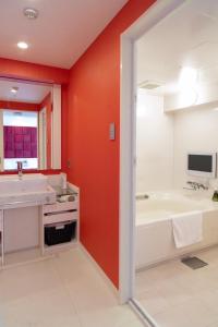 大阪hotel VR osaka的一间带红色墙壁、浴缸和水槽的浴室