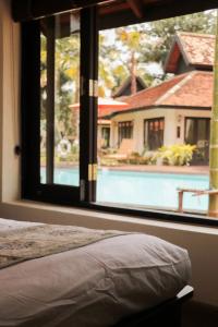 清迈Le Baan Thai Boutique Villa的卧室设有大窗户,享有游泳池的景色