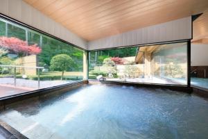 Komaba湯元ホテル阿智川的一座带大窗户的房屋内的游泳池