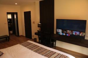 清迈Le Baan Thai Boutique Villa的一间卧室配有一张床和一台大屏幕平面电视