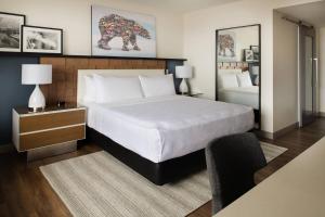 波特兰The Bidwell Marriott Portland的卧室配有一张白色大床和一把椅子