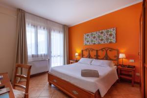 维拉西米乌斯iH Hotels Le Zagare Resort的一间卧室设有橙色墙壁、一张床和一把椅子