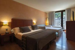 安道尔城Hotel Màgic Andorra的酒店客房设有两张床和窗户。
