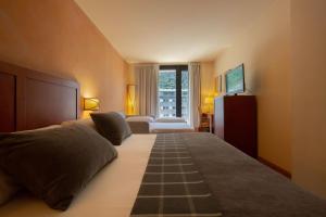 安道尔城Hotel Màgic Andorra的一间卧室设有一张大床和一个窗户。