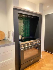 吕伐登Parkzicht的厨房配有带绿色瓷砖墙的炉灶。