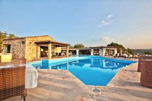 罗通多港ISA-Residence with swimming-pool in Porto Rotondo at only 500 m from the beach的一个带桌椅的度假村游泳池