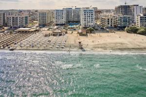 马马亚Infinity Breezes Apartment Beach Resort - parking的海滩上设有遮阳伞,海滩上设有建筑