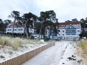 卢布明Blaumuschel Haus A Wohnung 10 Seeblick - DH的海滩上一排带有栅栏的白色建筑