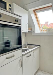 格洛米茨Bootshaus, App 3的白色的厨房设有水槽和窗户