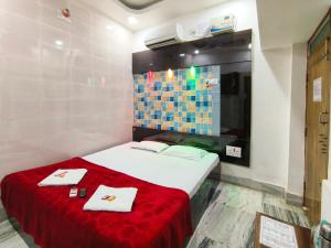 普里Bobby Premium Residency的一间卧室配有一张带红色毯子和毛巾的床