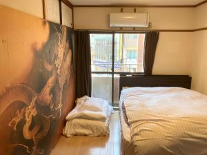 广岛Casa Viento Stay Inn的卧室配有一张床,墙上挂有绘画作品