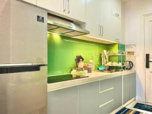 Ấp Ngọc HảiCăn Hộ Ocean Vista 1PN的厨房设有绿色的墙壁和白色的橱柜。