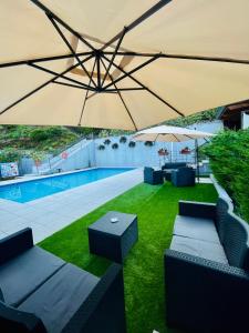 马斯诺维斯康蒂罗思澄堂勒酒店的游泳池上方配有桌椅的大型遮阳伞