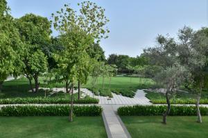 法里达巴德Courtyard by Marriott Aravali Resort的花园,有白色的楼梯,树木和草地