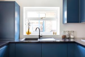 沃辛The Pride的厨房配有蓝色橱柜、水槽和窗户。