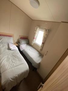 卡纳芬Beautiful 3 bed Static Caravan with Snowdon views in Caernarfon的一间小卧室,配有两张床和窗户