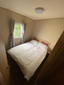 卡纳芬Beautiful 3 bed Static Caravan with Snowdon views in Caernarfon的卧室配有白色的床和窗户