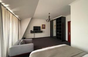 KachretʼiAmbassadori Kachreti Golf Resort的一间卧室配有一张床、一张沙发和一台电视