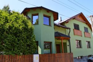 利普托斯基米库拉斯Ubytovanie Pri zvonici的黄色和绿色的房子,带围栏