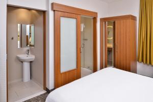 尔湾欧文韦恩机场/奥兰治春季山丘套房酒店的一间卧室设有一张床、一个卫生间和一个水槽