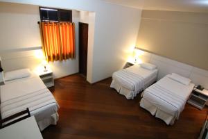 贝廷Samba Betim的客房设有两张床和一个带橙色窗帘的窗户。