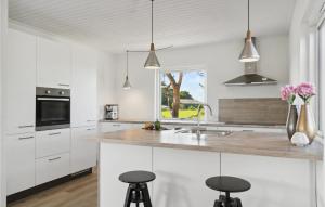 班霍尔姆Awesome Home In Bandholm With House Sea View的厨房配有白色橱柜和带凳子的台面