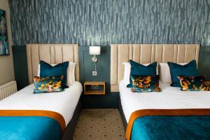 拉辛赫Lahinch Coast Hotel and Suites的蓝色墙壁客房的两张床