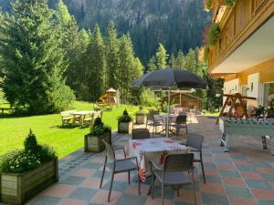 坎皮泰洛迪法萨Alpenhotel Panorama的一个带桌椅和遮阳伞的庭院