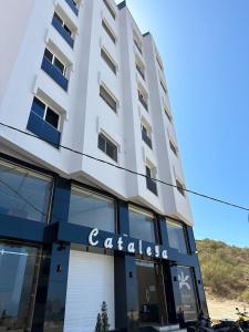 胡塞马Hotel Cataleya Al-Hoceima的一座高大的白色建筑,上面有标志