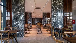 哥里Gori Inn的餐厅设有木桌、椅子和黑色大理石墙壁。