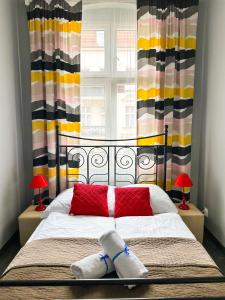 波兹南Expolis Residence - City Center MTP TARGI- Reception 24h的一间卧室配有一张带红色枕头的床和一扇窗户