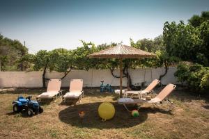 卡拉马基Tarsia Homes & Suites的院子里的一组椅子和一把伞