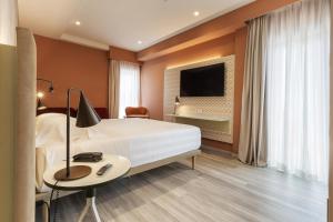 罗马Adesso Hotel的酒店客房设有一张床、一张书桌和一台电视机。