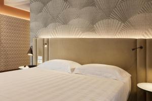 罗马Adesso Hotel的卧室配有带白色枕头的大床