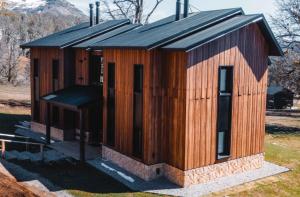 圣马丁德洛斯El Refugio Ski & Summer Lodge的一座带黑色屋顶的小型木制建筑