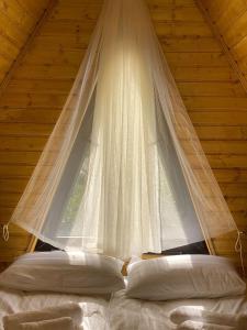 卡兹贝吉Sunny Side Cottage的卧室配有挂在床上的白色窗帘