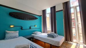波瓦-迪瓦尔津Sardines and Friends Hostel 04的一间设有两张床的客房和墙上的冲浪板