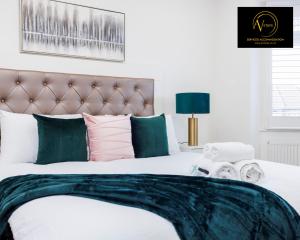 锡德卡普Stylish 4 Bedroom Home by AV Stays Short Lets Sidcup with Free Parking的卧室配有带绿色和粉红色枕头的大床