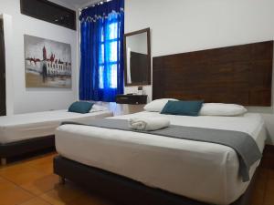 巴兰基亚hotel san nicolas colonial的一间卧室设有两张床,窗户配有蓝色窗帘
