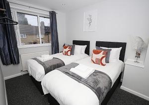 伦敦Must stay 3 Bedroom house near Greenwich and Blackheath- Ideal for families and contractors的配有白色和橙色枕头的客房内的两张床