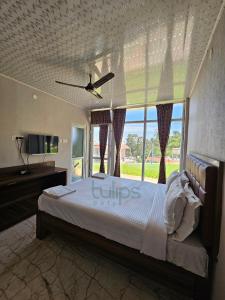 乌提Tulips Village Resorts的一间卧室设有一张床和一个大窗户