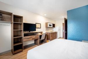 肯代尔WoodSpring Suites Miami Southwest的客房设有1张床、1张办公桌和1台电视。