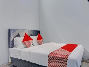 茂物Capital O 92765 J&b Smart Sentul的一间卧室配有红色和白色枕头的床