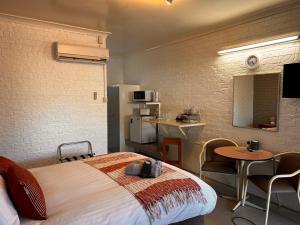 格伦因尼斯Jillaroo Motor Inn的酒店客房设有一张床铺、一张桌子和一间厨房。