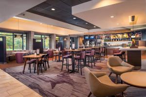 赫恩登Courtyard by Marriott Dulles Airport Herndon/Reston的一间带桌椅的餐厅和一间酒吧