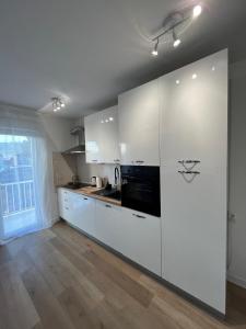 斯普利特Apartment TIM的厨房铺有木地板,配有白色橱柜。